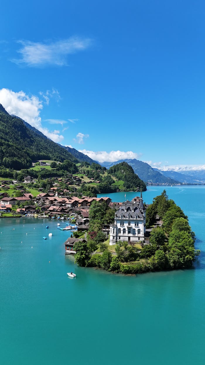 A picturesque villa nestled on an island in a vibrant turquoise lake surrounded by Swiss Alps.
