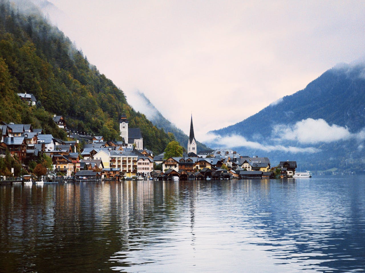 About Misty morning in Hallstatt, Austria with serene lake and quaint village.