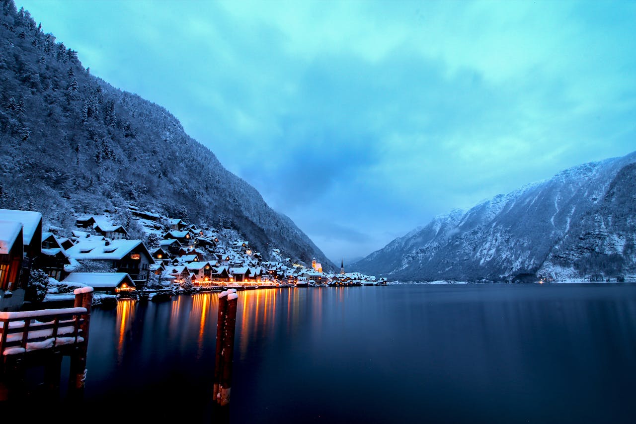 Captivating winter landscape of Hallstatt with illuminated houses and snow-covered mountains at twilight.